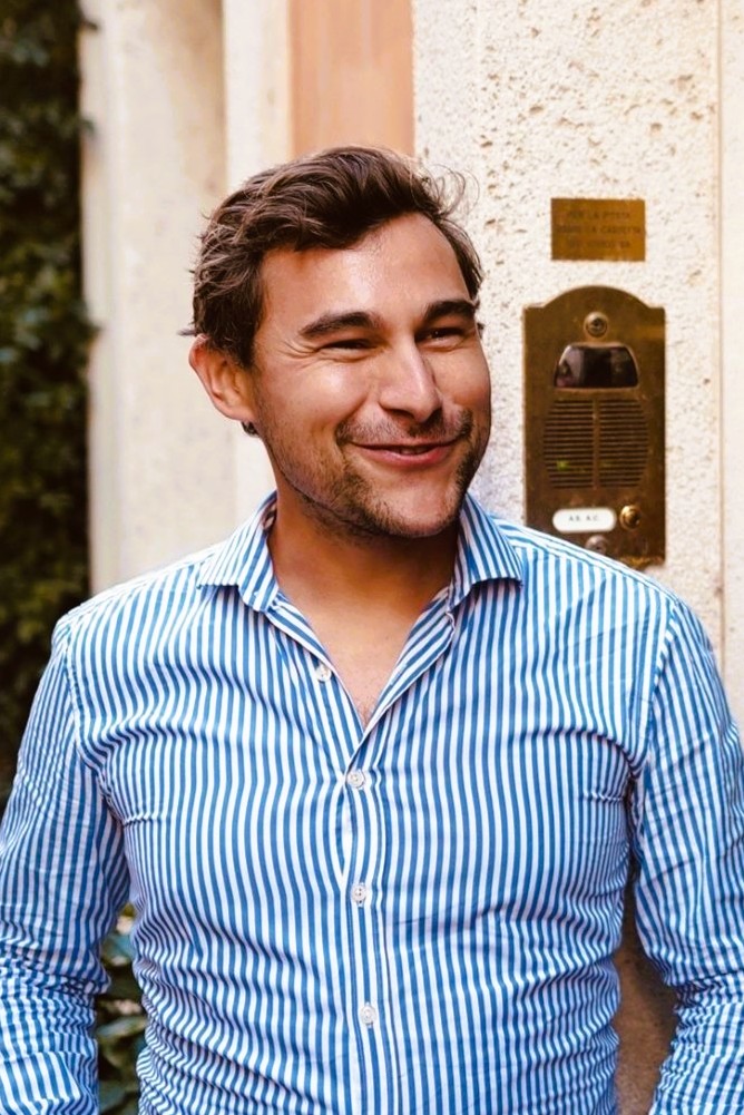Jeanine White smiling in a red plaid shirt and tortoise shell glasses
